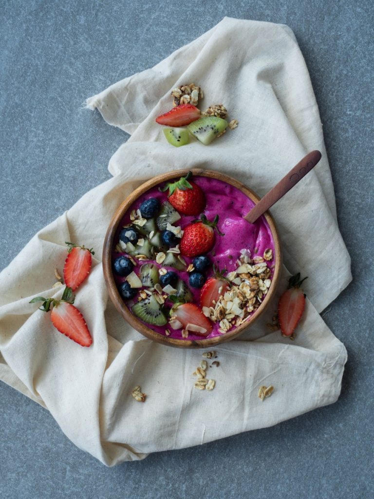 Smoothie bowl z borówkami i truskawkami w drewnianej misce na lnianym obrusie